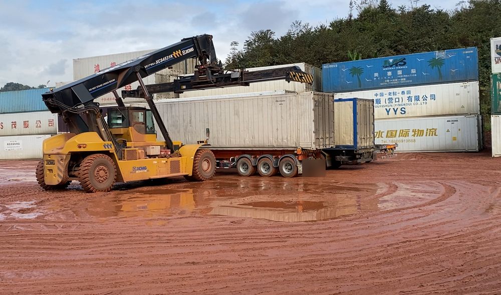 A reach stacker moving a container at a transfer yard on the Thailand → Laos → Vietnam route
